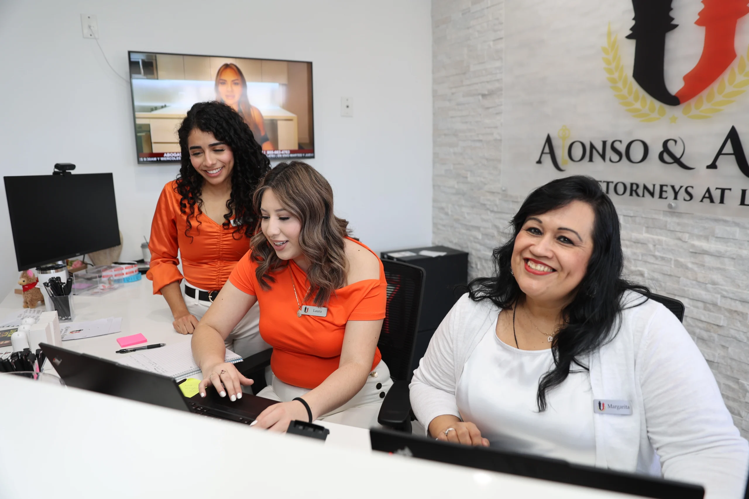 Equipo de abogados de inmigración en Phoenix atendiendo clientes en recepción de despacho legal.