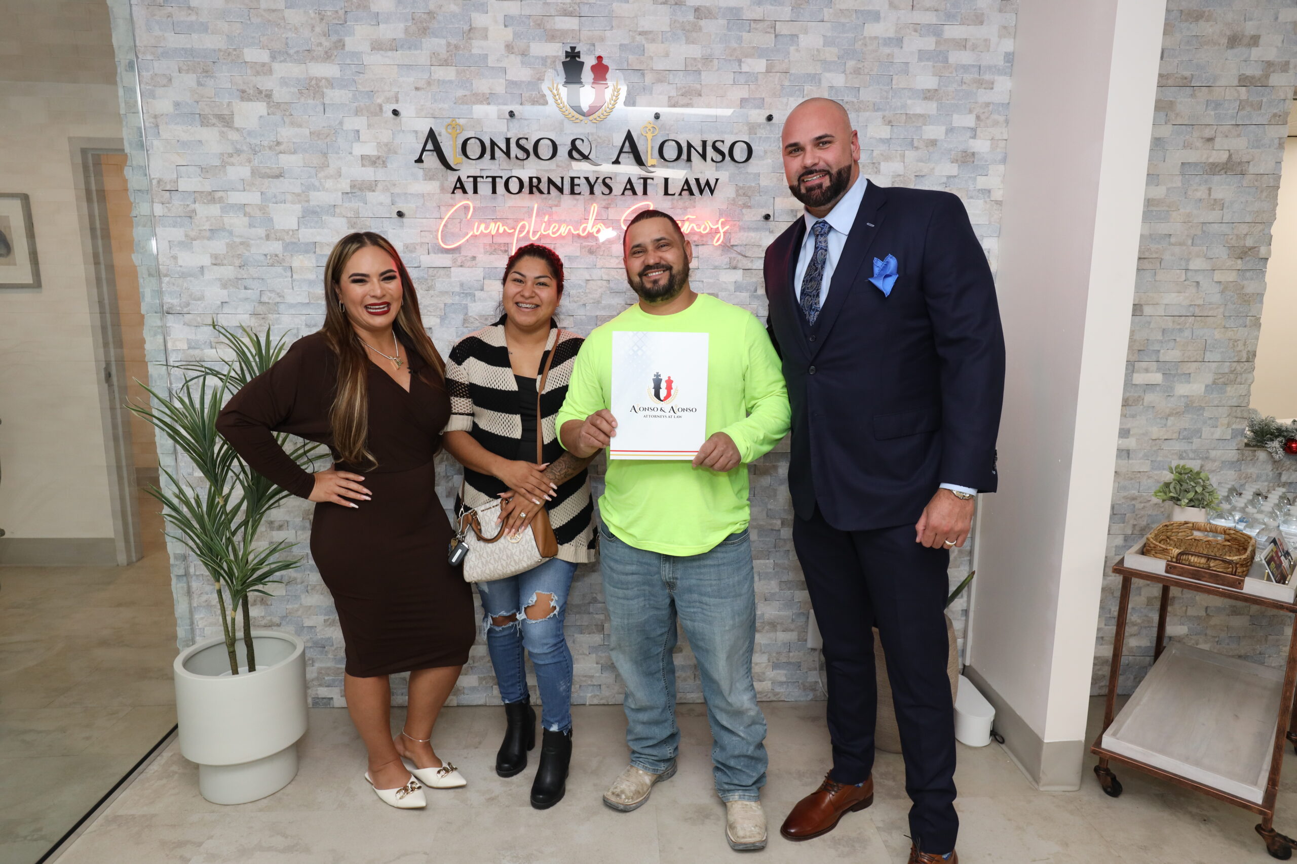 Abogados de un bufete especializado en inmigración celebran la aprobación de un caso con un cliente en la oficina de Alonso & Alonso.