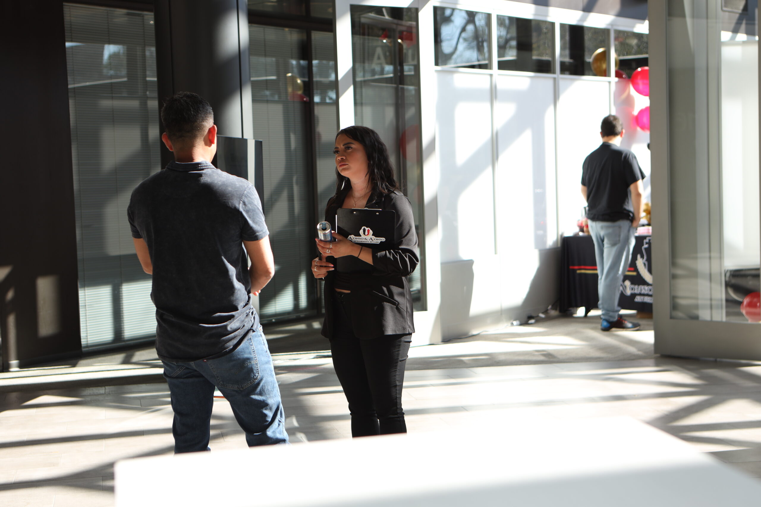 Miembro del equipo legal de inmigración conversando con un cliente durante un evento comunitario